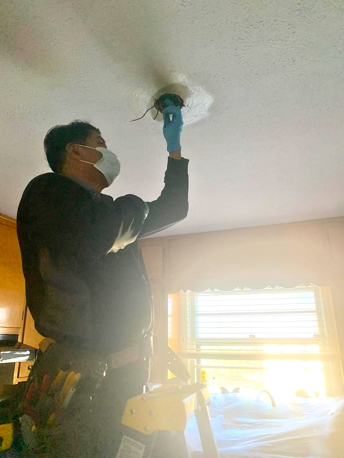 Nunez Electric technician wiring a ceiling light fixture